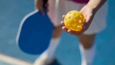 Pickle ball player serving a ball