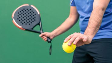 Professional monitor of padel holding a yellow ball and black racket. Sport game