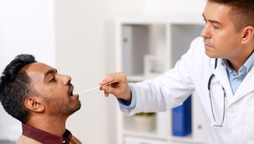 doctor examining patient throat at clinic
